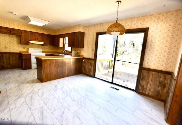 kitchen with a wainscoted wall, electric range, and wallpapered walls