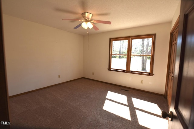 unfurnished room featuring a textured ceiling, carpet flooring, visible vents, and baseboards