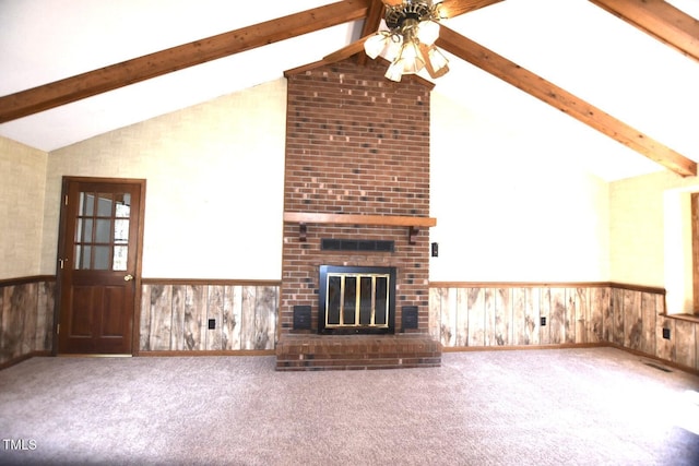 unfurnished living room featuring lofted ceiling with beams, a wainscoted wall, wood walls, carpet floors, and a brick fireplace