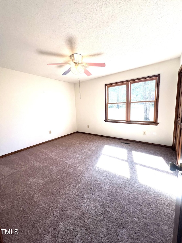 carpeted empty room featuring ceiling fan, visible vents, baseboards, and a textured ceiling