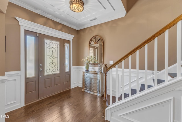 foyer with a wainscoted wall, visible vents, stairway, dark wood finished floors, and crown molding