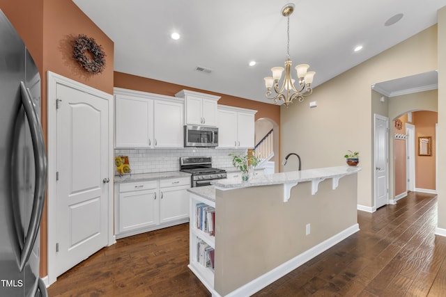 kitchen with white cabinetry, visible vents, arched walkways, and stainless steel appliances