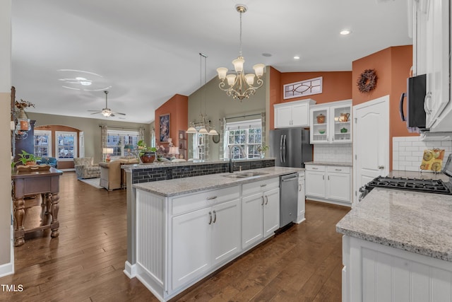 kitchen with dark wood finished floors, open floor plan, stainless steel appliances, white cabinetry, and a sink