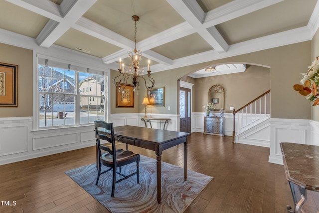 dining area with arched walkways, dark wood-type flooring, and beam ceiling