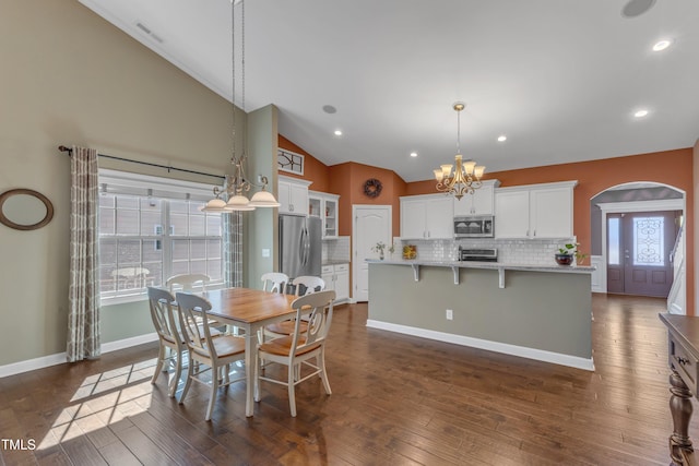 dining space with arched walkways, baseboards, dark wood finished floors, and a notable chandelier