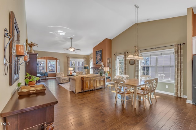 dining room with dark wood-type flooring, arched walkways, baseboards, and a ceiling fan