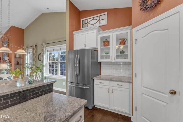 kitchen with decorative backsplash, dark wood finished floors, glass insert cabinets, freestanding refrigerator, and vaulted ceiling