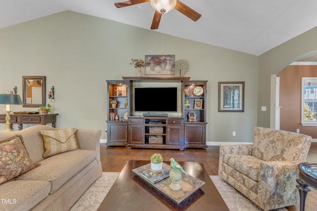 living area with arched walkways, lofted ceiling, a ceiling fan, wood finished floors, and baseboards