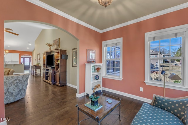 living room with baseboards, ornamental molding, dark wood-type flooring, and a ceiling fan