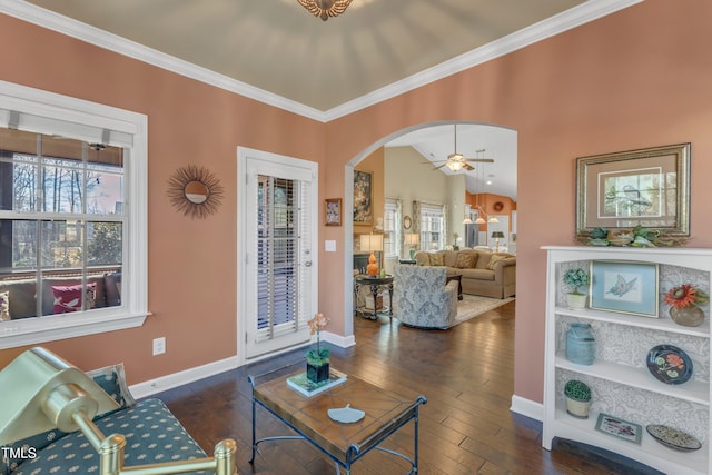 living room featuring baseboards, arched walkways, dark wood finished floors, ceiling fan, and crown molding