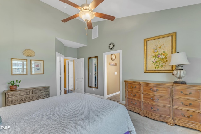 carpeted bedroom featuring a towering ceiling, baseboards, and a ceiling fan