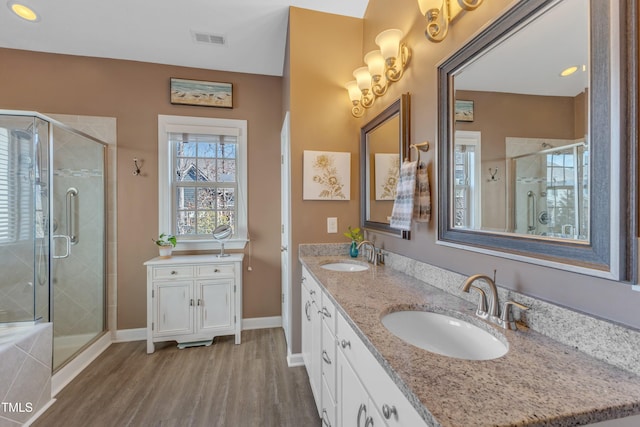 bathroom featuring a stall shower, visible vents, a sink, and wood finished floors