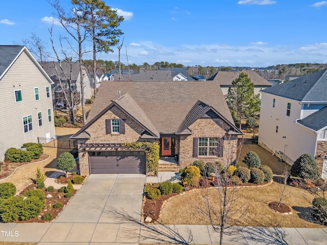 traditional home with a garage, a shingled roof, concrete driveway, fence, and brick siding