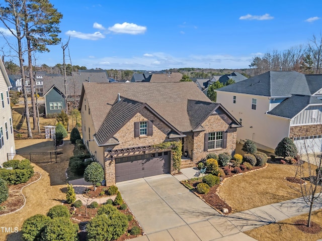 traditional home with driveway, a residential view, an attached garage, fence, and brick siding