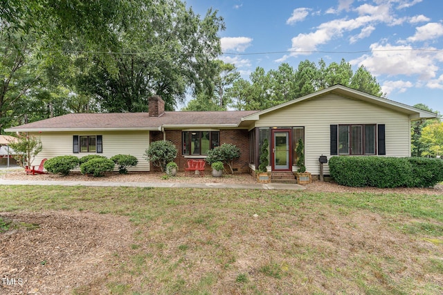 ranch-style home featuring a front yard, brick siding, a chimney, and entry steps