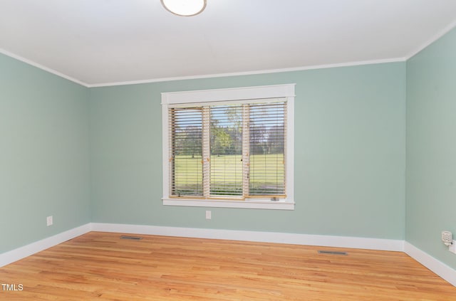 spare room featuring baseboards, wood finished floors, and ornamental molding