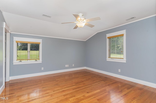 spare room featuring light wood-style flooring, visible vents, vaulted ceiling, and crown molding