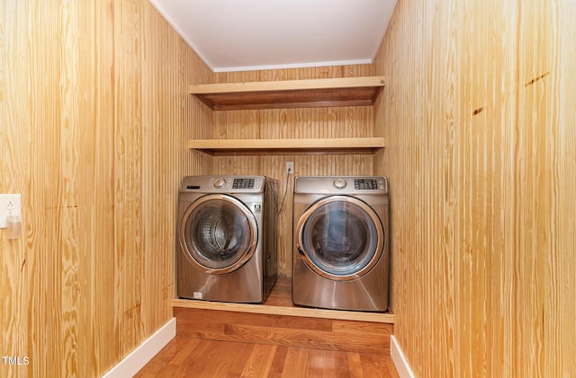 laundry area with laundry area, crown molding, washer and clothes dryer, and wood finished floors