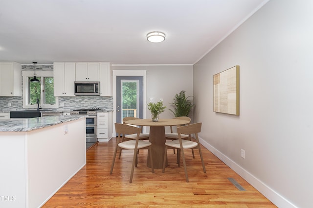 kitchen featuring visible vents, white cabinetry, appliances with stainless steel finishes, decorative backsplash, and pendant lighting