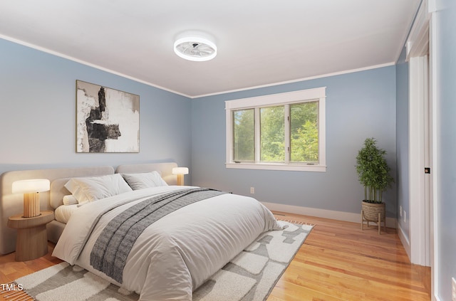 bedroom featuring light wood-style floors, baseboards, and ornamental molding