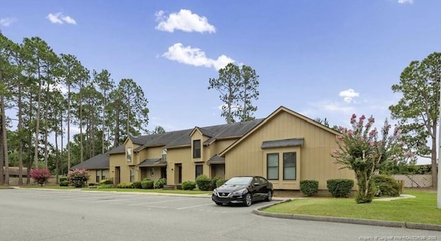 view of front facade with uncovered parking and a front yard