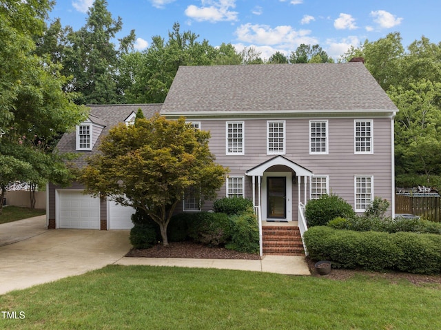 colonial inspired home featuring a front yard, fence, concrete driveway, and roof with shingles