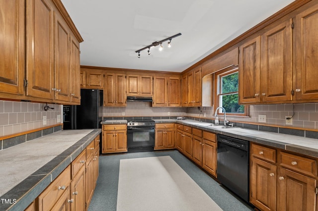 kitchen with tasteful backsplash, brown cabinets, under cabinet range hood, black appliances, and a sink