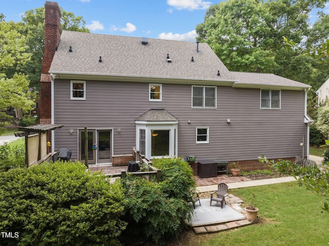 rear view of property with a yard, a patio, a shingled roof, and a chimney