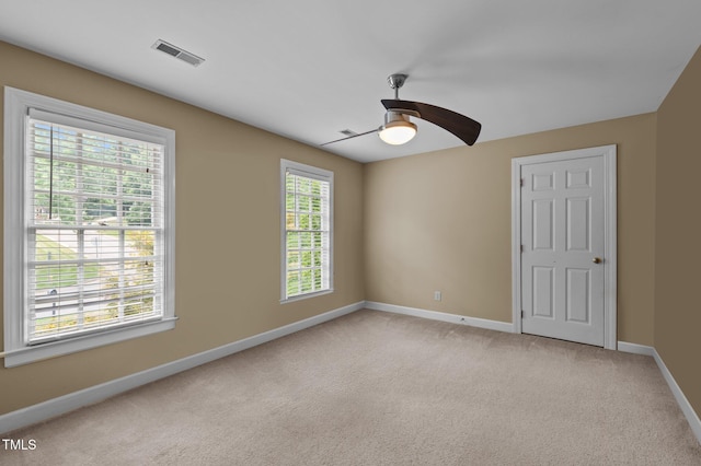 spare room featuring baseboards, ceiling fan, visible vents, and light colored carpet