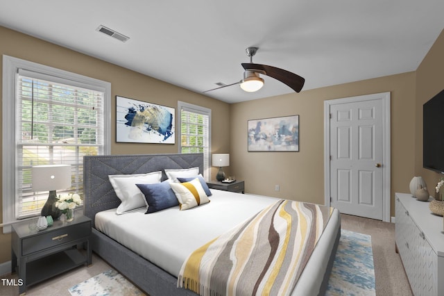 bedroom featuring a ceiling fan, visible vents, and light carpet