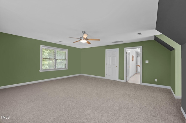 interior space with visible vents, baseboards, light colored carpet, lofted ceiling, and ceiling fan