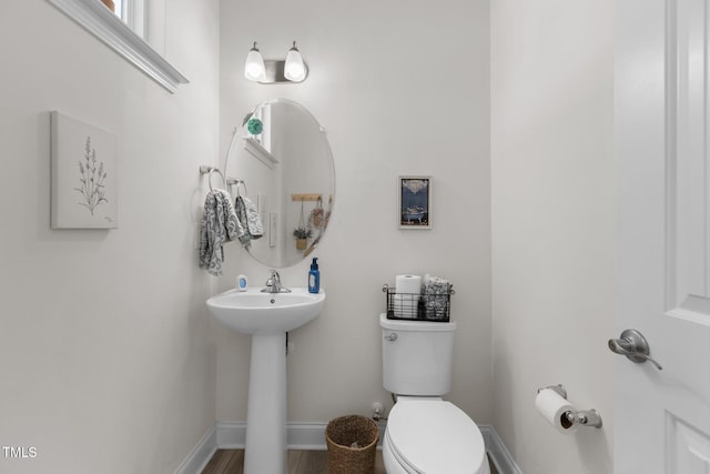 bathroom with toilet, baseboards, a sink, and wood finished floors