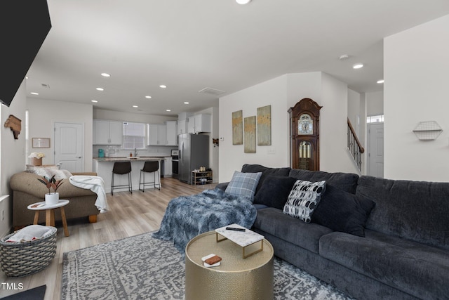 living room featuring light wood-style flooring, stairway, and recessed lighting