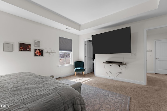 carpeted bedroom featuring a tray ceiling, visible vents, and baseboards