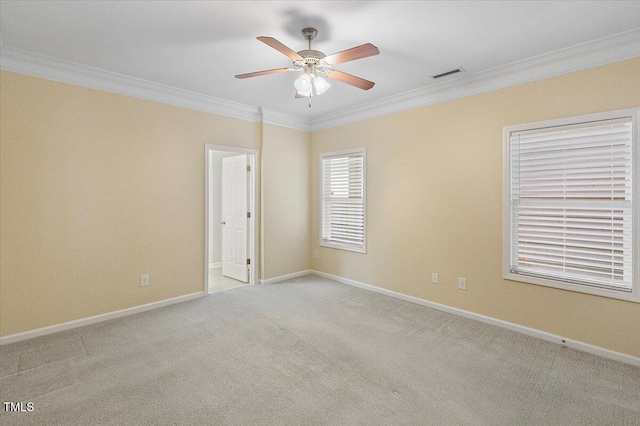 empty room with baseboards, visible vents, a ceiling fan, light colored carpet, and crown molding