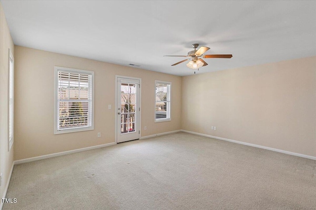 spare room featuring baseboards, ceiling fan, visible vents, and light colored carpet