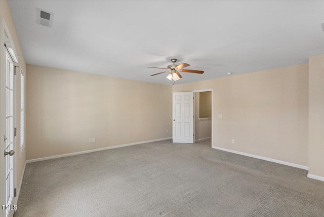 spare room featuring light colored carpet, visible vents, ceiling fan, and baseboards