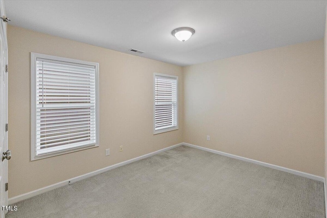 empty room with light carpet, visible vents, and baseboards