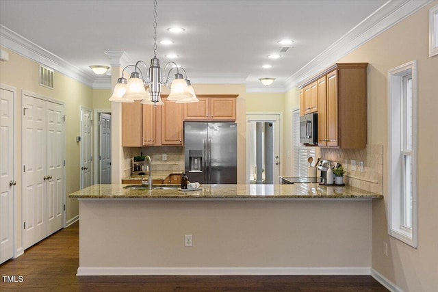 kitchen with dark stone counters, stove, stainless steel refrigerator with ice dispenser, pendant lighting, and a sink