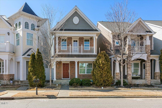 view of front of property with a standing seam roof, brick siding, and a balcony