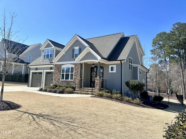 craftsman-style house with driveway, a garage, stone siding, roof with shingles, and fence