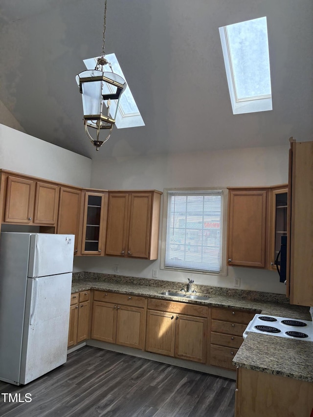 kitchen featuring a skylight, white appliances, brown cabinets, and a sink