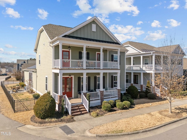 view of front of home with covered porch, board and batten siding, a standing seam roof, fence, and metal roof