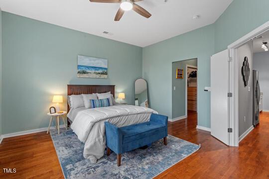 bedroom with baseboards, wood finished floors, and freestanding refrigerator