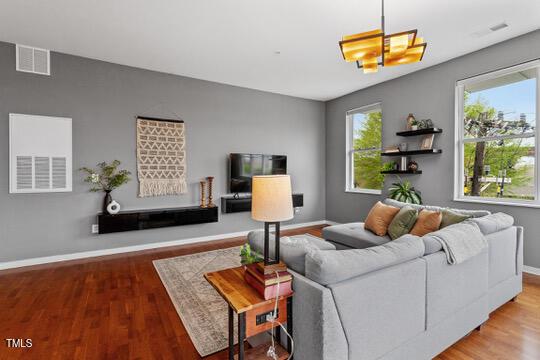 living room featuring baseboards, visible vents, and wood finished floors