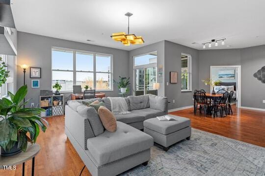 living room featuring track lighting, wood finished floors, and baseboards