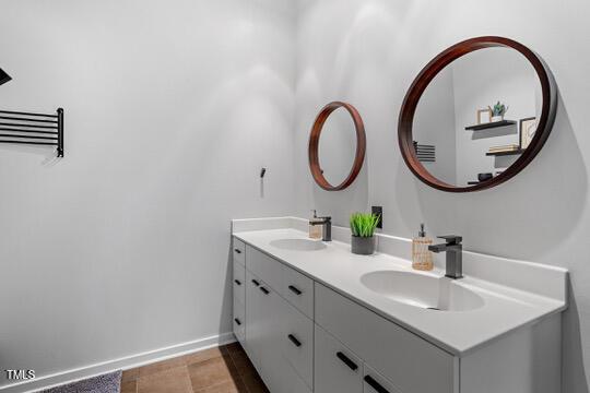 bathroom with a sink, baseboards, and double vanity