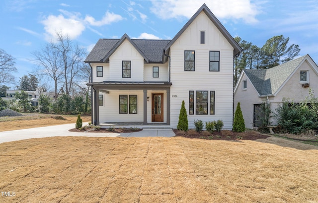 modern farmhouse featuring covered porch, board and batten siding, a shingled roof, and a front lawn