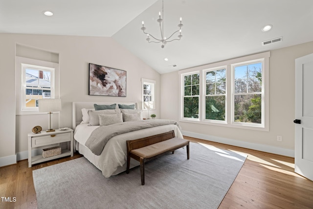 bedroom featuring visible vents, light wood-style flooring, baseboards, lofted ceiling, and a chandelier