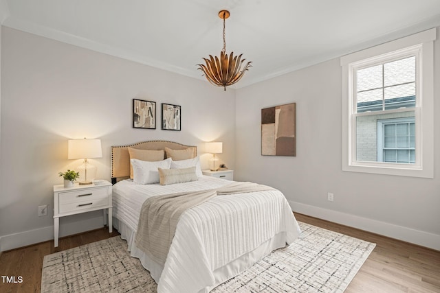 bedroom with a chandelier, light wood finished floors, and baseboards